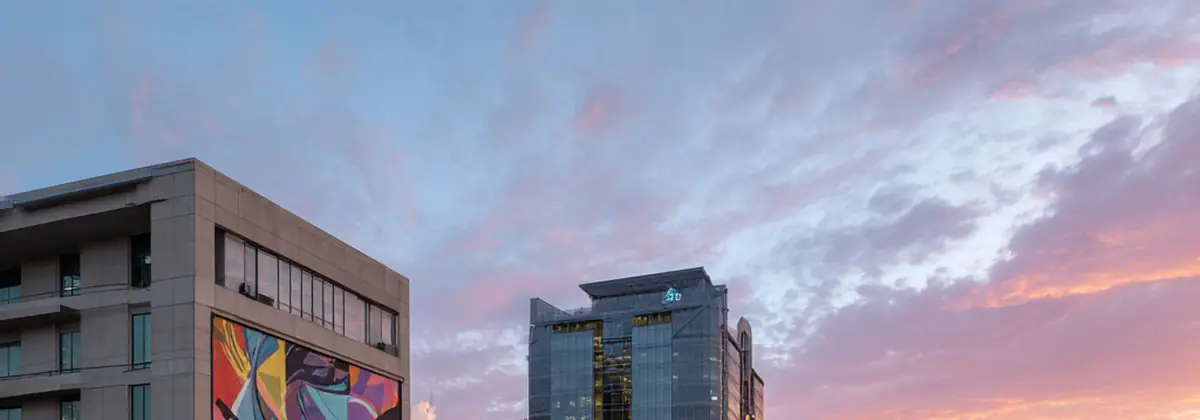 Downtown San Jose street with colorful mural on building and tech towers at dusk